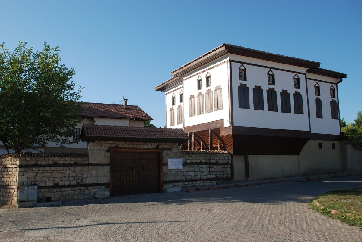 Restore edilmiş Ayanağa Konağı — beyaz cepheli, ahşap payandalı tarihî Divriği konağı ve taş avlu duvarı
