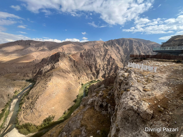 The Çaltı winding between rocky slopes; on the right, a rocky spur with a letter sign and the glass terrace
