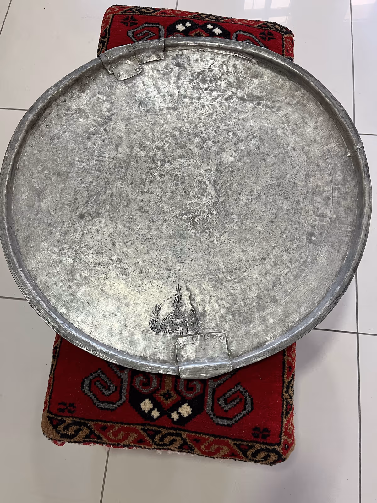 Round metal object with surface wear and repair traces at its edge