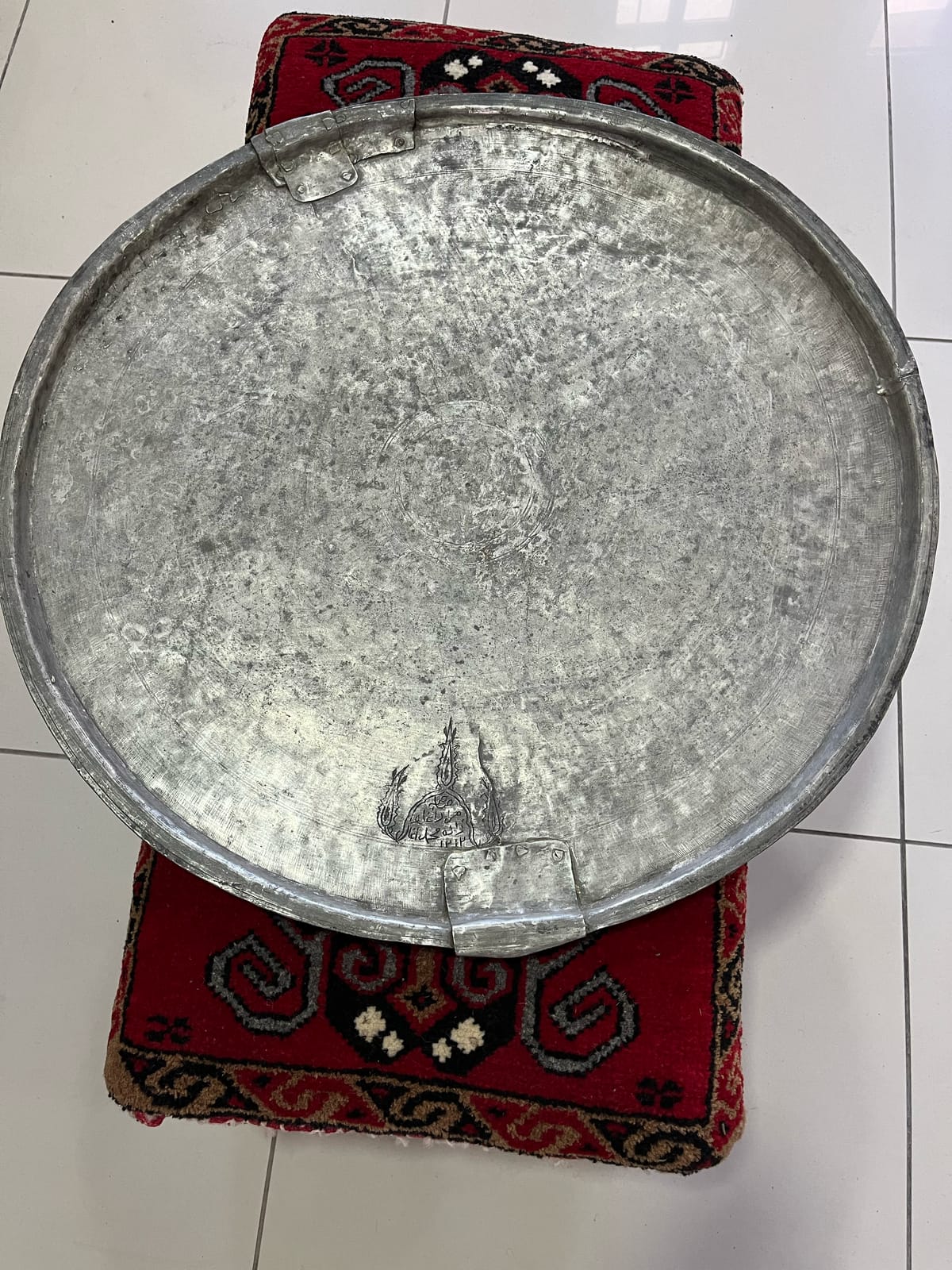 Yüzeyinde aşınma ve kenarında onarım izleri görülen yuvarlak metal eşya