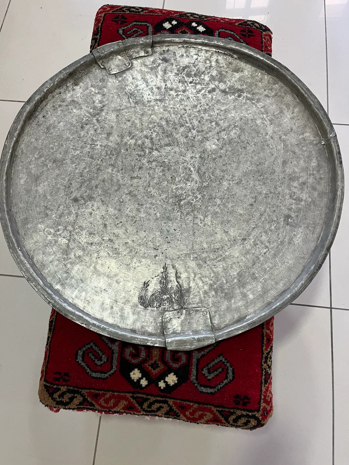 Yüzeyinde aşınma ve kenarında onarım izleri görülen yuvarlak metal eşya