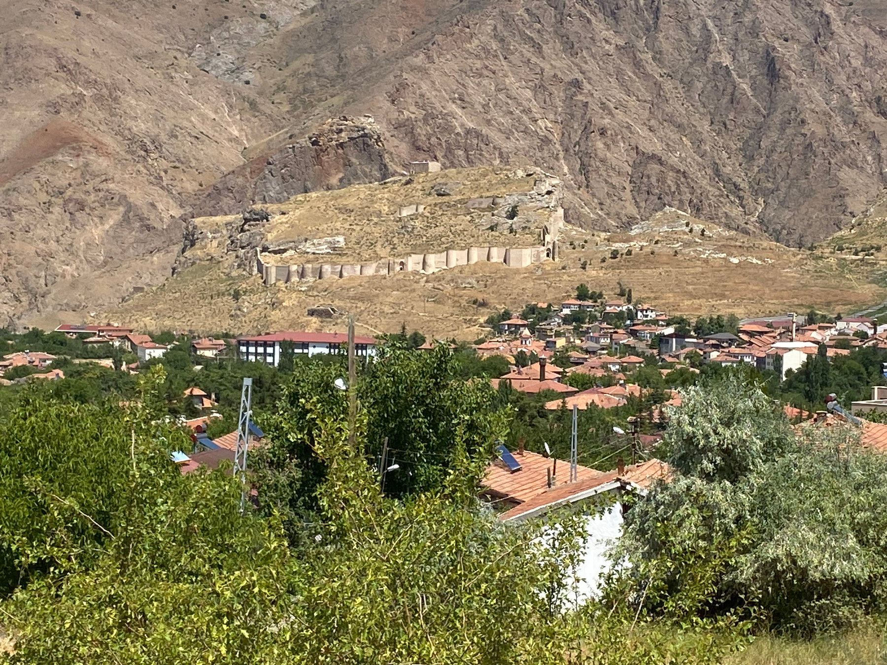 Yamaçta uzanan kale surları ve hemen altında kentin kırmızı çatıları