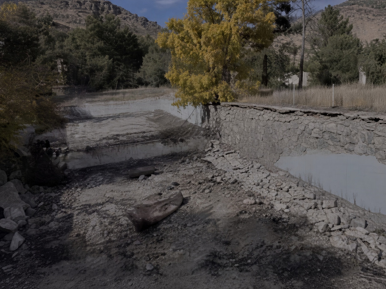 Suyu çekilmiş, taş ve beton duvarlı bir havuz